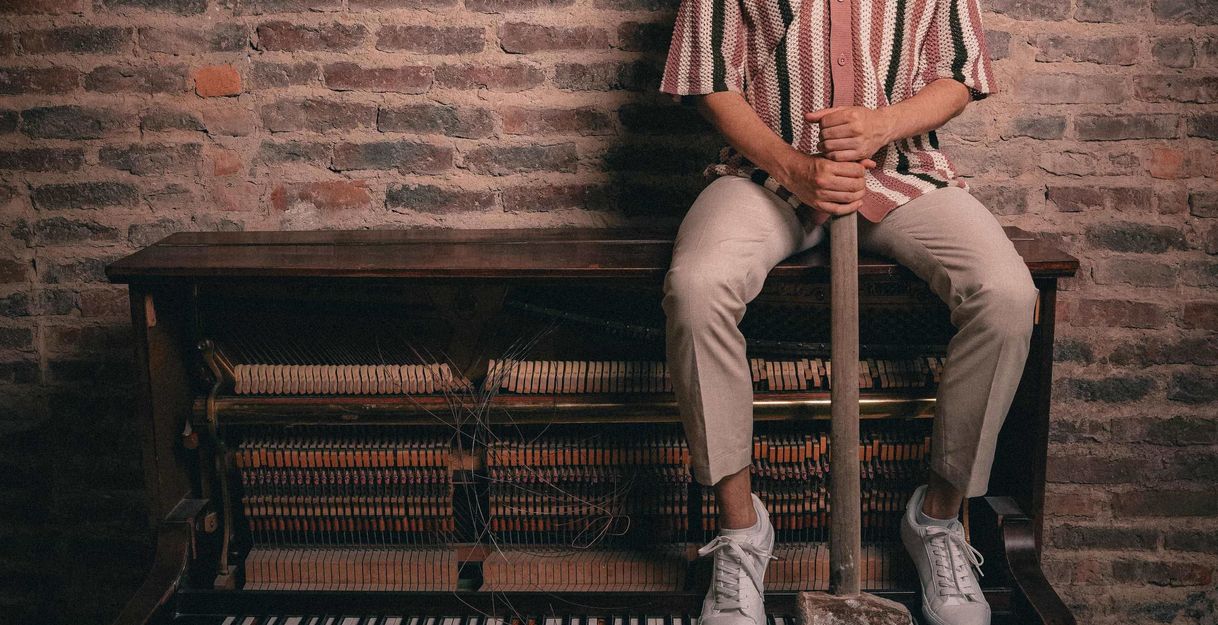 Mann sitzt auf einem Piano