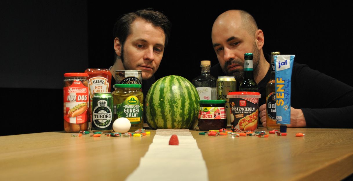 Zwei Männer und davor Lebensmittel auf einem Tisch