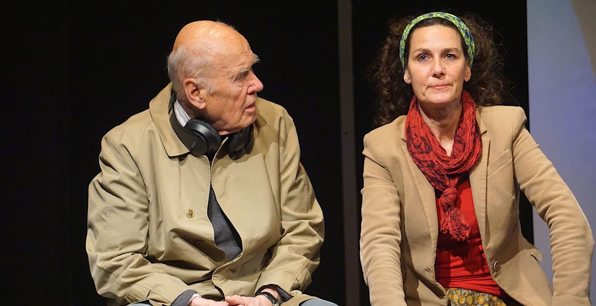 Älterer Mann und eine Frau unterhalten sich nebeneinander sitzend