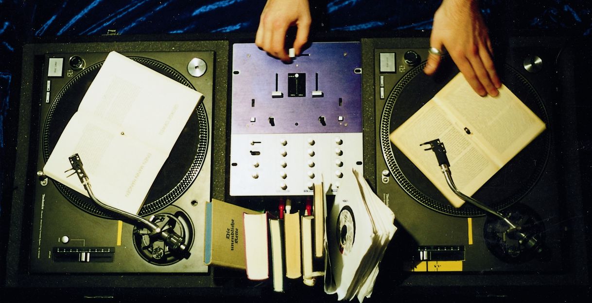 Bild zeigt ein Mischpult von oben mit zwei Händen.