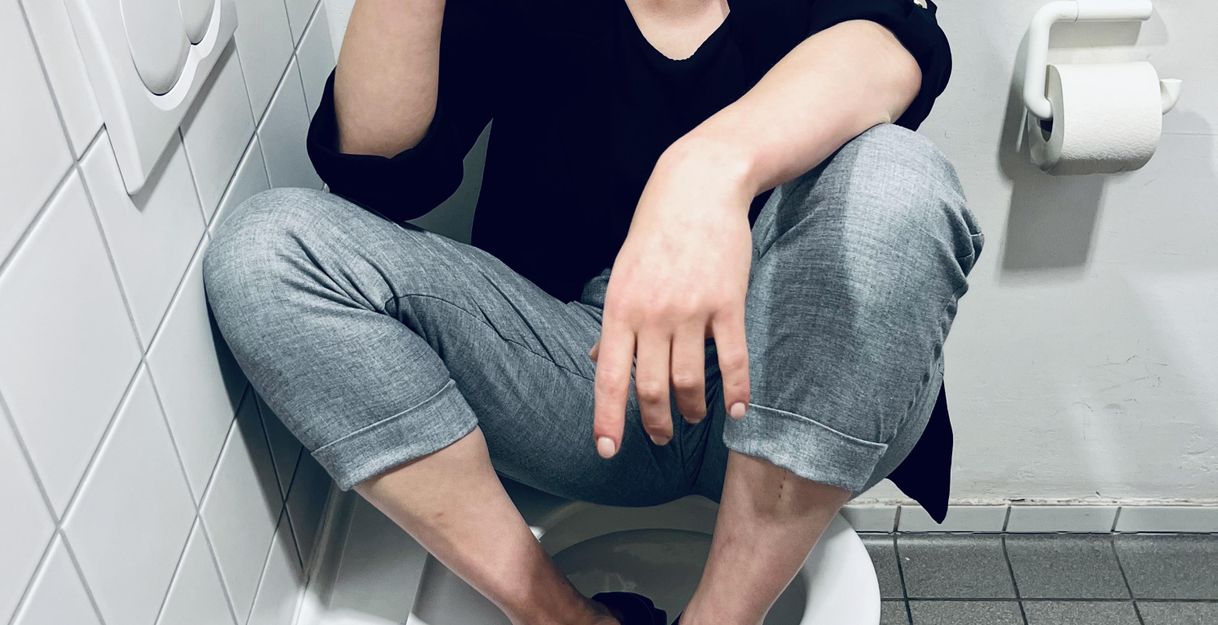 Frau raucht sitzend auf einer Teoilette