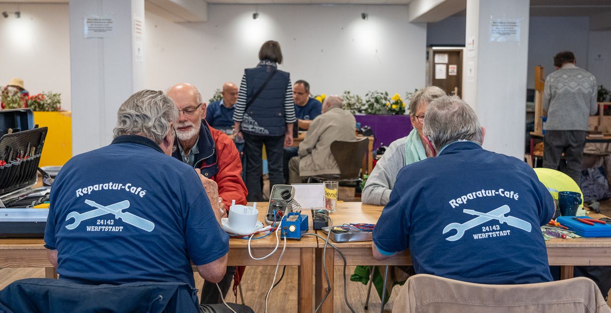 Reparateure mit Besucherinnen und Besuchern beim Reparatur-Café Gaarden